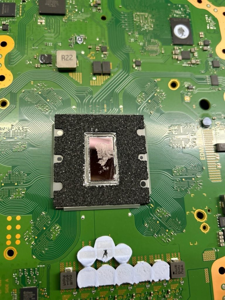 Placa base de PS5 con el metal líquido del APU degradado antes de su sustitución